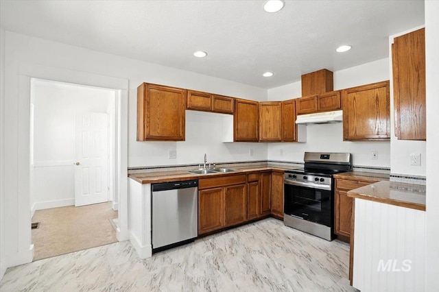 101 E 2nd St, Emmett, ID 83617 - kitchen with appliances with stainless steel finishes, under cabinet range hood, brown cabinets, recessed lighting, and light marble finish floors