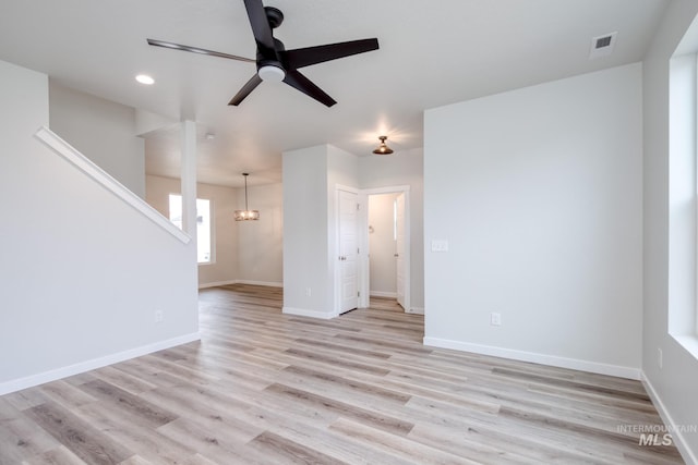 2839 N Rocky Bottom Way, Kuna, ID 83634 - unfurnished living room featuring baseboards, ceiling fan with notable chandelier, light wood-type flooring, and visible vents