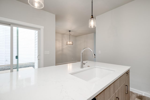 2839 N Rocky Bottom Way, Kuna, ID 83634 - kitchen with hanging light fixtures, plenty of natural light, light stone countertops, and a sink