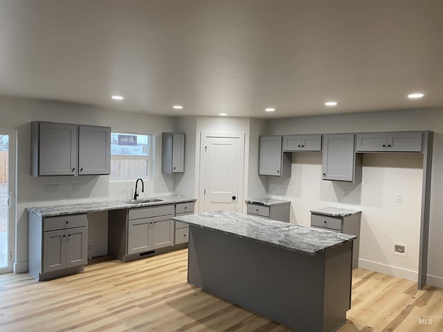 kitchen featuring sink, a kitchen island, gray cabinetry, and light hardwood / wood-style floors