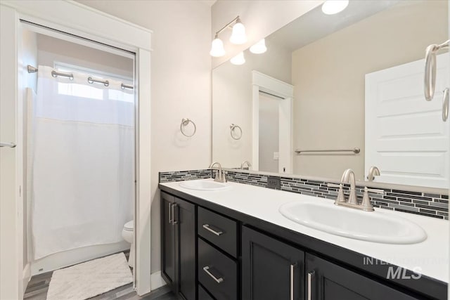 3023 E Tusa St, Meridian, ID 83642 - bathroom featuring double vanity, toilet, tasteful backsplash, and wood finished floors