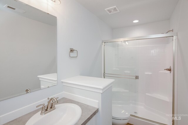 bathroom with a shower with door, vanity, and toilet