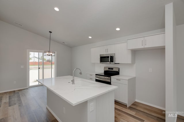 kitchen featuring stainless steel appliances, a kitchen island with sink, decorative light fixtures, light hardwood / wood-style flooring, and white cabinets