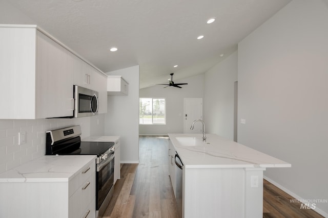 kitchen featuring sink, an island with sink, appliances with stainless steel finishes, and vaulted ceiling