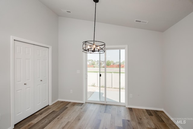 unfurnished dining area with light hardwood / wood-style flooring, high vaulted ceiling, and a notable chandelier