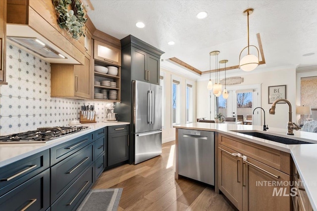 kitchen featuring pendant lighting, a sink, stainless steel appliances, crown molding, and light countertops