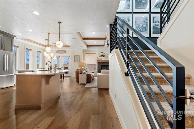 kitchen with a sink, light countertops, freestanding refrigerator, a textured ceiling, and dark wood-style flooring