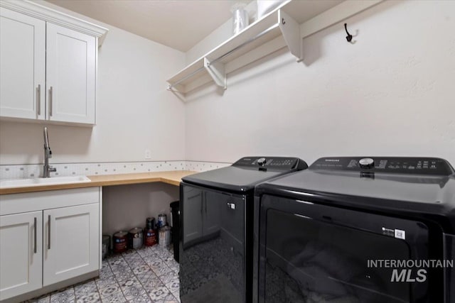 washroom with cabinet space, washing machine and dryer, and a sink