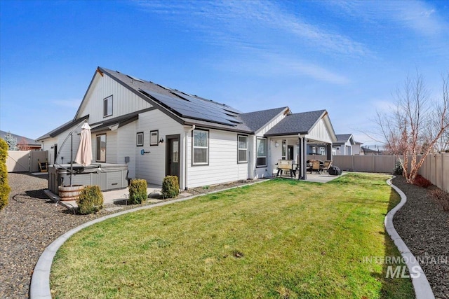 rear view of house featuring a patio, solar panels, a fenced backyard, and a hot tub