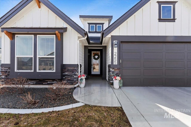 view of front of home featuring concrete driveway, a garage, board and batten siding, and stone siding