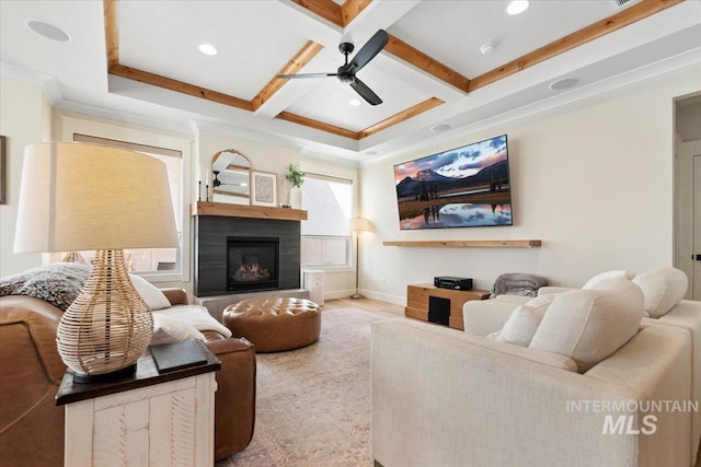 living area featuring baseboards, ceiling fan, beam ceiling, a glass covered fireplace, and coffered ceiling