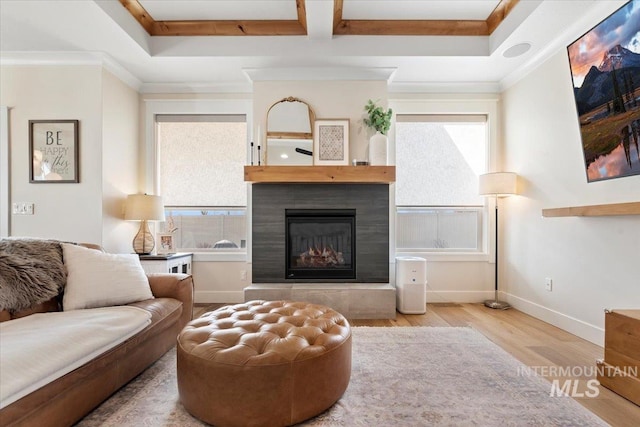 living room featuring a glass covered fireplace, crown molding, wood finished floors, and baseboards