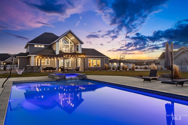 pool at dusk featuring a patio area and an in ground hot tub