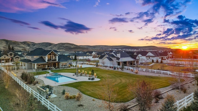 exterior space with a patio area, a fenced in pool, a lawn, and a mountain view