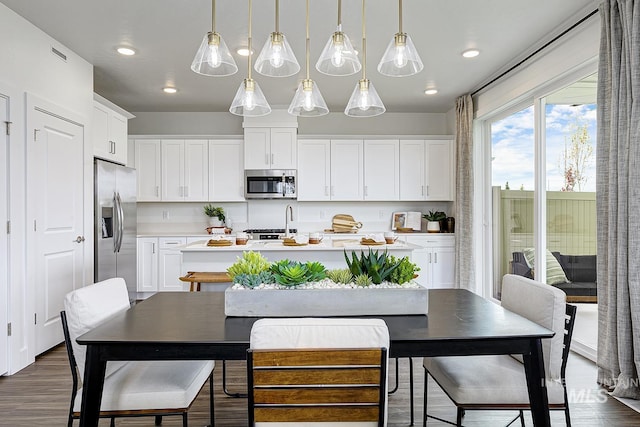 8002 W Fern St, Eagle, ID 83616 - kitchen with stainless steel appliances, a center island with sink, light countertops, white cabinetry, and pendant lighting
