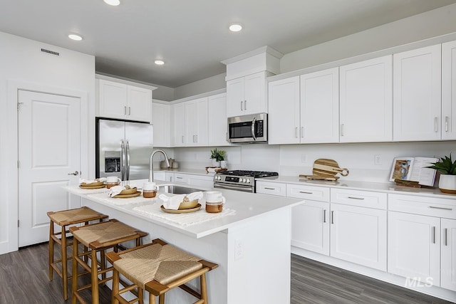 8002 W Fern St, Eagle, ID 83616 - kitchen featuring appliances with stainless steel finishes, a sink, dark wood finished floors, a kitchen bar, and white cabinetry