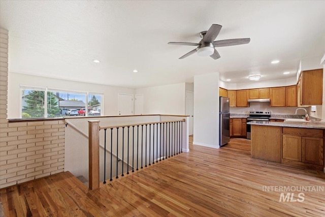 kitchen with light hardwood / wood-style flooring, stainless steel appliances, brick wall, sink, and ceiling fan