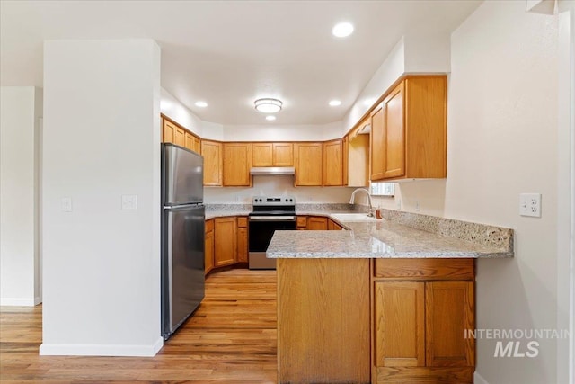 kitchen with light hardwood / wood-style flooring, appliances with stainless steel finishes, sink, and light stone counters