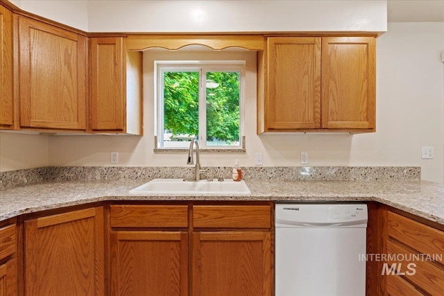 kitchen with light stone countertops, sink, and white dishwasher