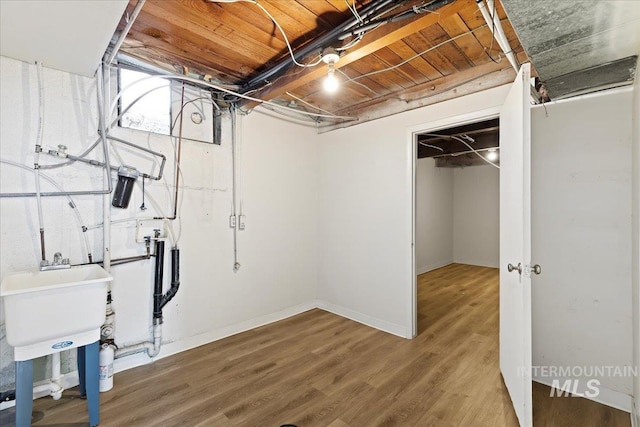 basement with hardwood / wood-style flooring and sink