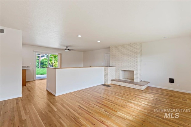 unfurnished living room with light hardwood / wood-style floors, ceiling fan, and a brick fireplace