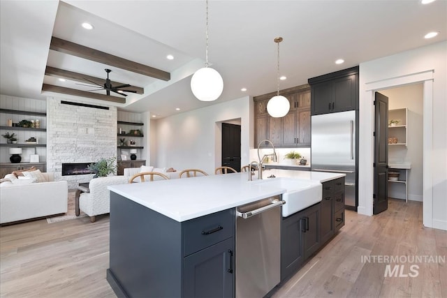 kitchen with light wood-style floors, appliances with stainless steel finishes, light countertops, ceiling fan, and a sink