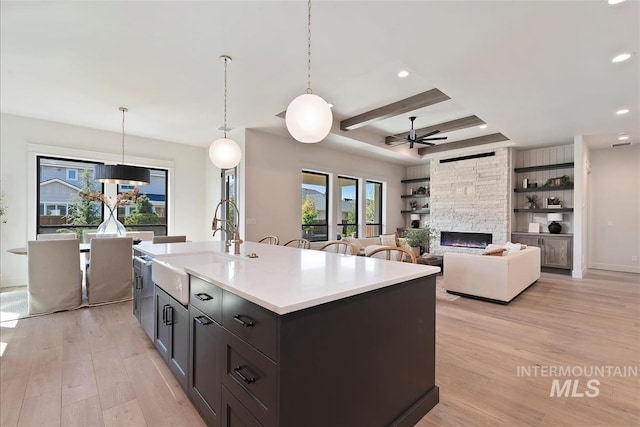 kitchen featuring a sink, ceiling fan, light wood-style floors, and a fireplace