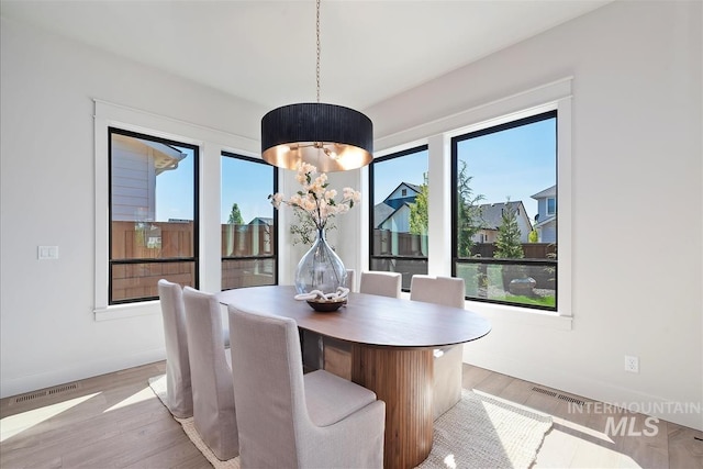 dining area with a wealth of natural light, visible vents, baseboards, and light wood-style floors