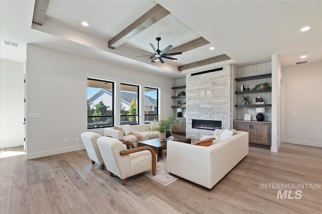 living area featuring a fireplace, light wood finished floors, baseboards, visible vents, and a ceiling fan