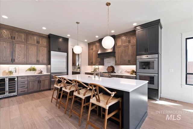 kitchen with beverage cooler, backsplash, appliances with stainless steel finishes, and light countertops