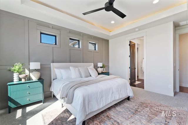 carpeted bedroom featuring visible vents, recessed lighting, a raised ceiling, and multiple windows