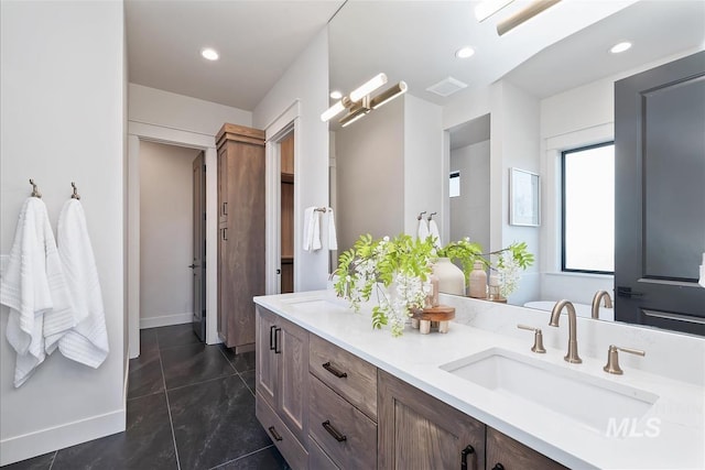 bathroom featuring double vanity, baseboards, recessed lighting, and a sink