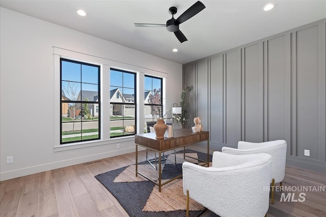 office space with ceiling fan, baseboards, a decorative wall, and light wood-style floors
