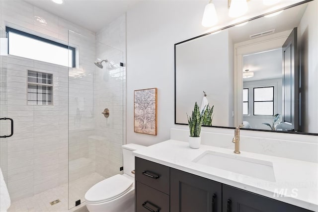 bathroom with toilet, a stall shower, visible vents, and vanity