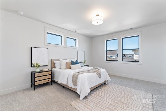 bedroom with baseboards, visible vents, and light carpet