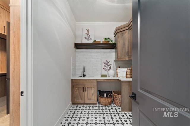 bar featuring baseboards, tasteful backsplash, and a sink