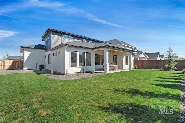 rear view of property featuring a lawn, a fenced backyard, and a patio area