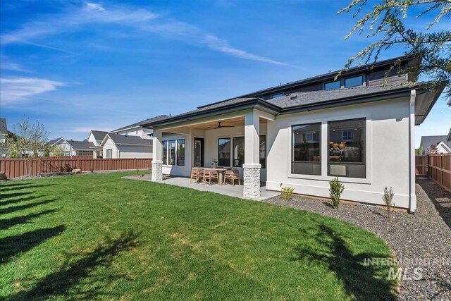 rear view of property featuring a patio, a yard, a fenced backyard, a ceiling fan, and stucco siding