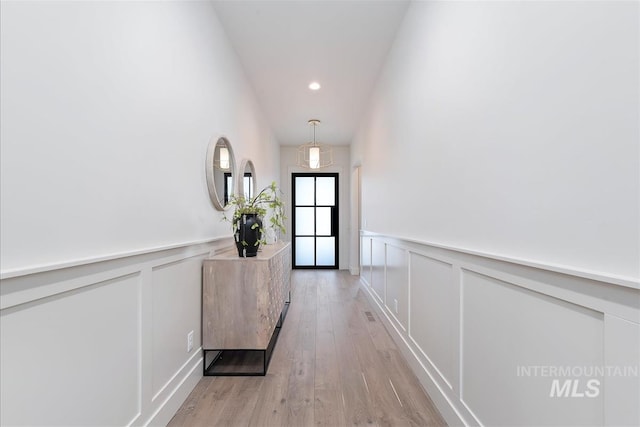hallway with recessed lighting, wainscoting, a decorative wall, and light wood-type flooring