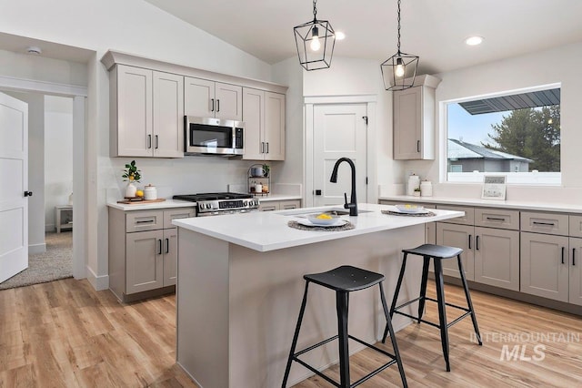 kitchen featuring range, stainless steel microwave, vaulted ceiling, gray cabinetry, and a sink