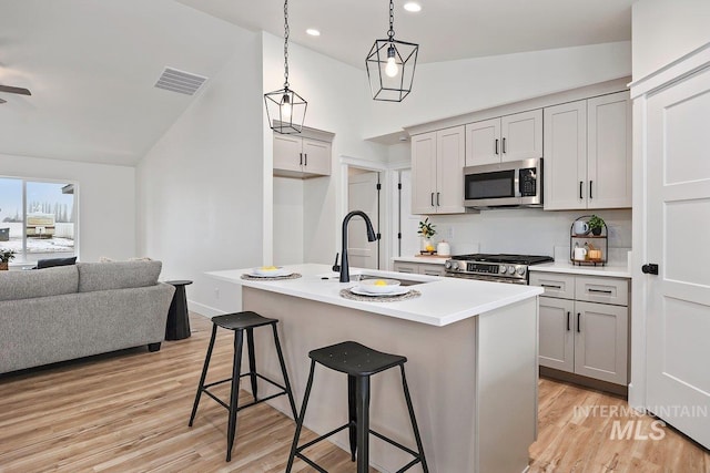 kitchen with stainless steel appliances, visible vents, light wood-style flooring, open floor plan, and a kitchen breakfast bar