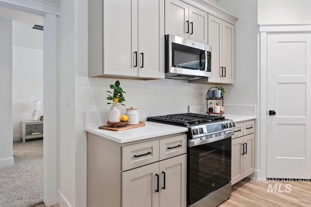 kitchen with visible vents, light wood-style floors, baseboards, light countertops, and appliances with stainless steel finishes