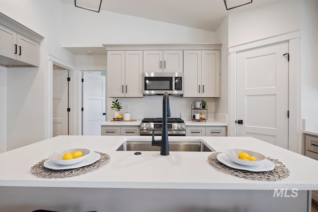 kitchen featuring stainless steel appliances, light countertops, vaulted ceiling, and a sink