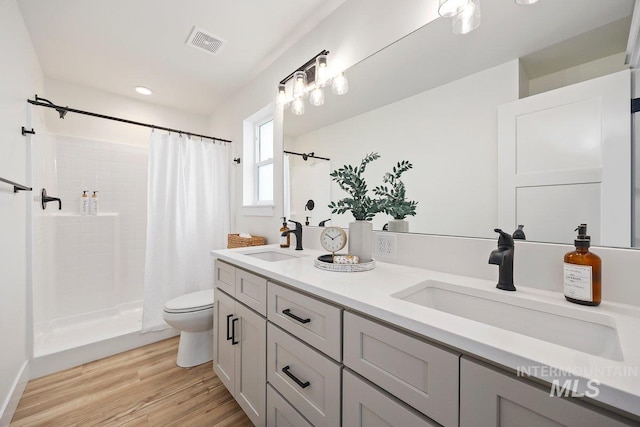 bathroom with visible vents, a sink, toilet, and wood finished floors