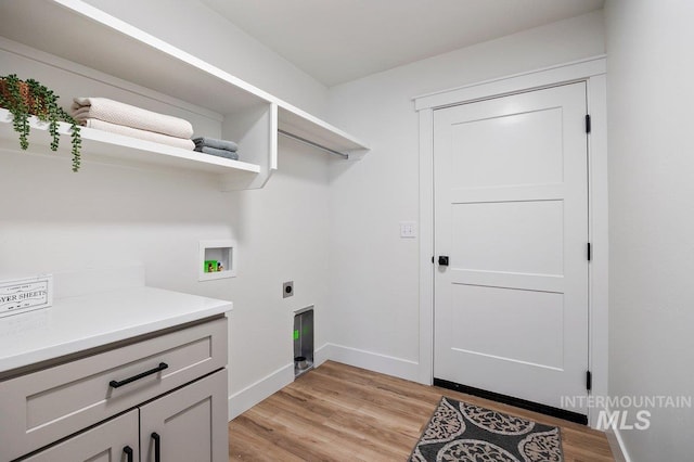 clothes washing area with light wood finished floors, cabinet space, baseboards, hookup for an electric dryer, and washer hookup