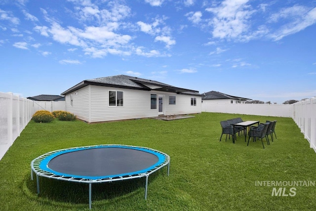 back of property featuring a patio area, a fenced backyard, a trampoline, and a yard