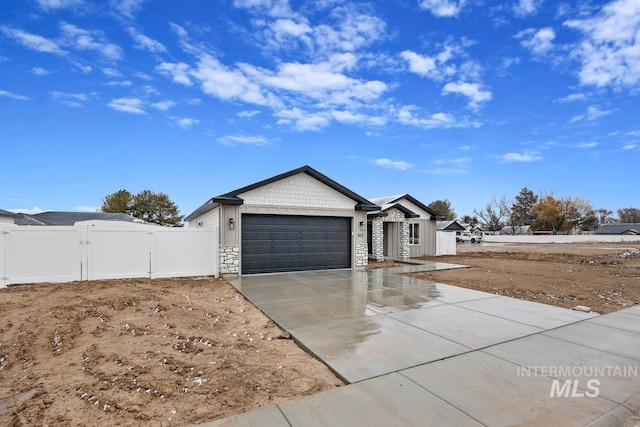 ranch-style house with concrete driveway, an attached garage, a gate, fence, and stone siding