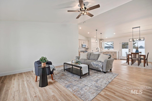 living area featuring baseboards, ceiling fan, vaulted ceiling, light wood-type flooring, and recessed lighting