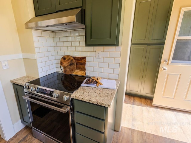 kitchen with stainless steel range with electric cooktop, green cabinetry, decorative backsplash, light wood-type flooring, and under cabinet range hood