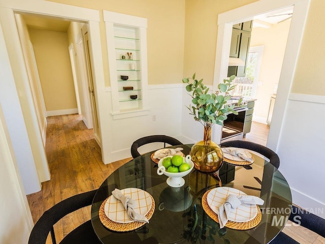 dining space with built in features and wood finished floors